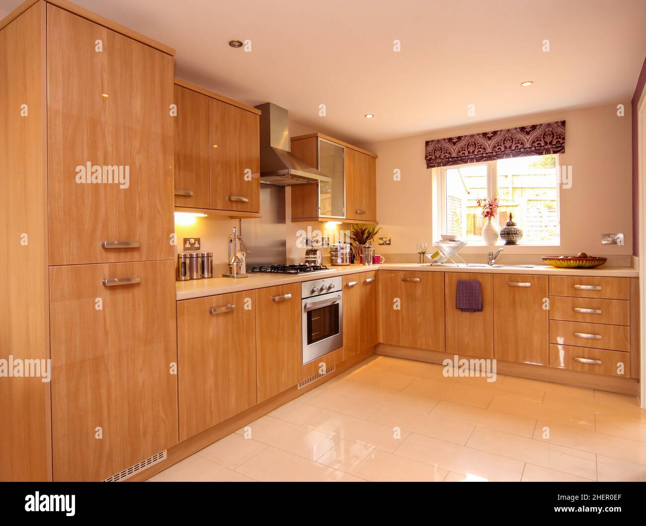 Modern kitchen with high gloss wood effect units, tiled floor,window