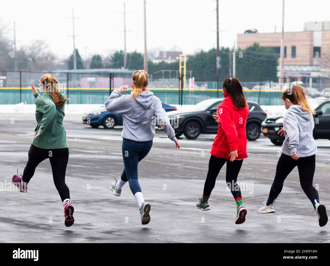 High school track runners running speed drills in a wet and icy parking