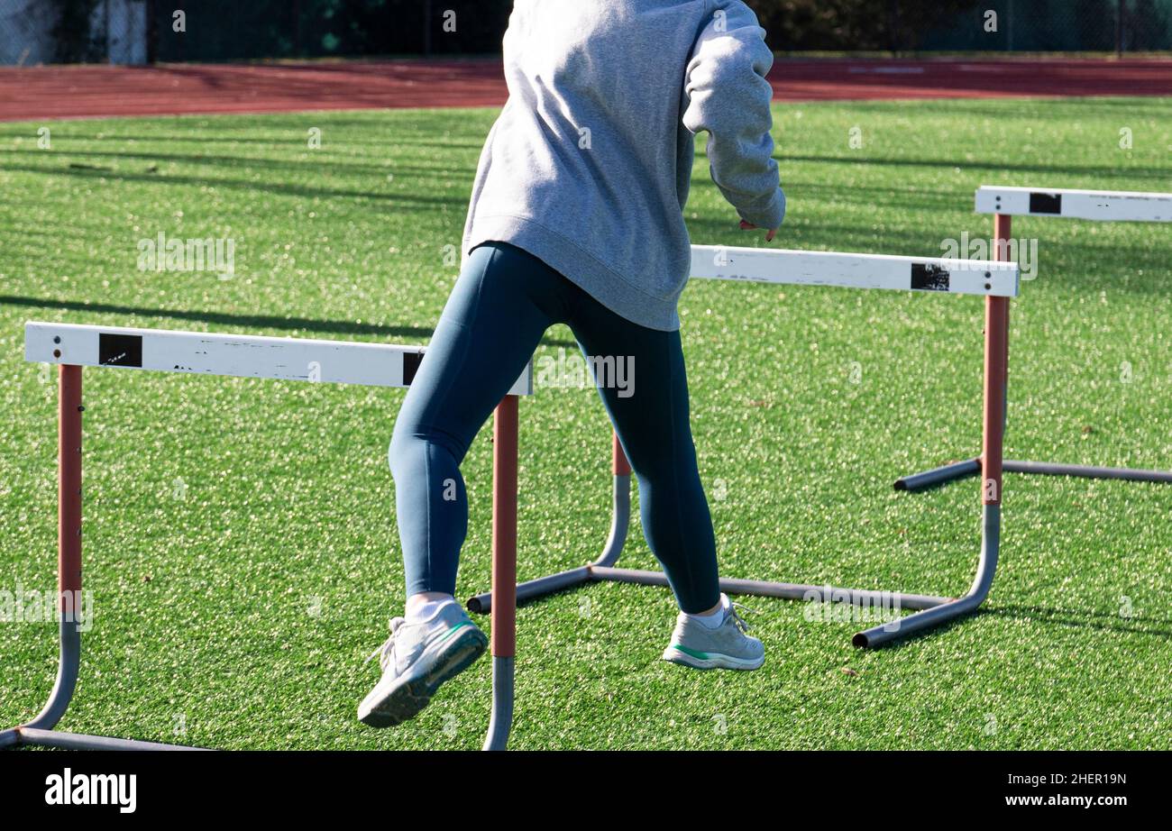 Rear view of a high school Hurdle runner performing the trail leg drill