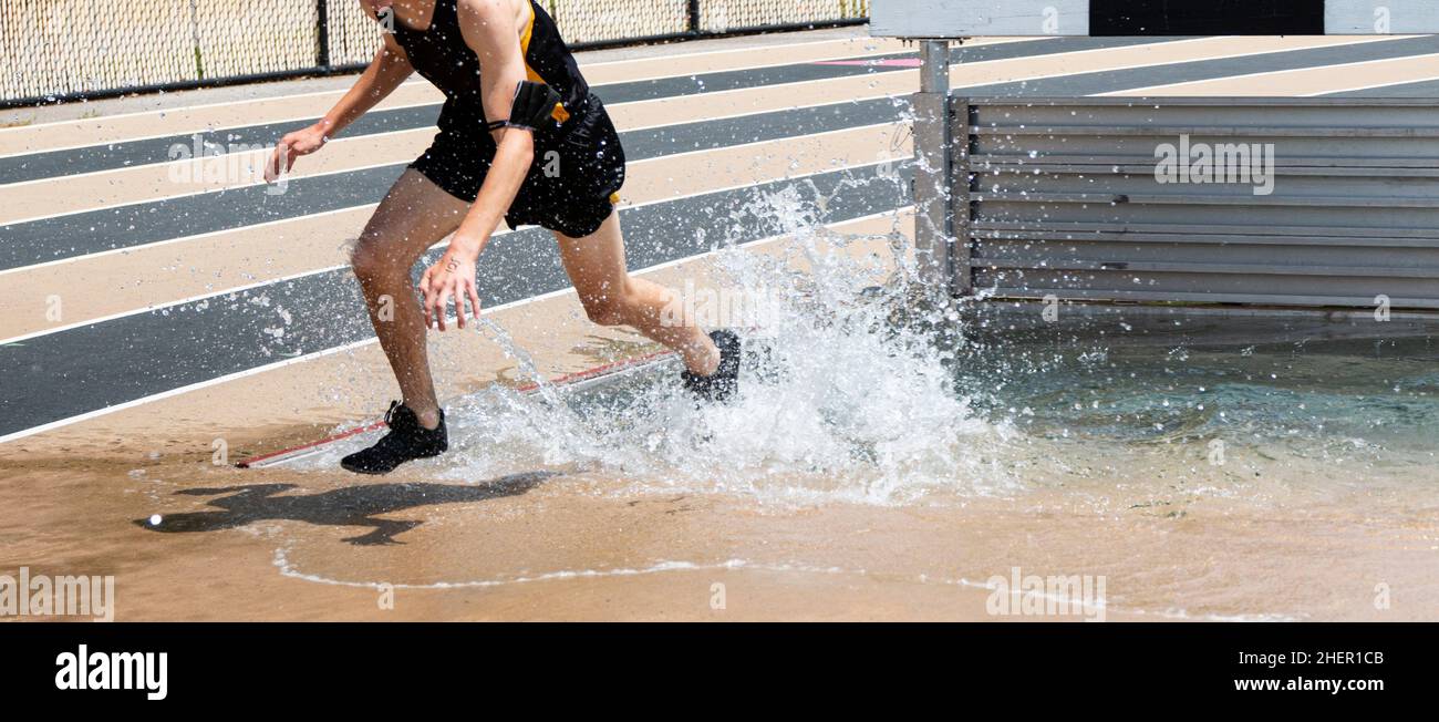 A high school boy is splashing in the water as he is exiting the