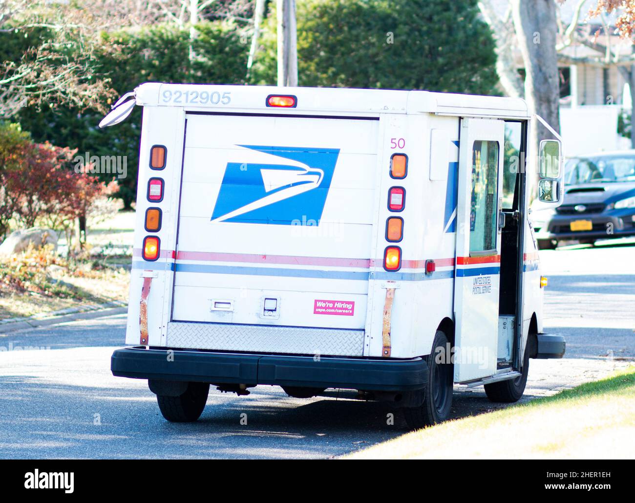 Babylon, New York, USA - 12 December 2021: A united States Postal Delivery truck is parked on a residential street in Babylon Village while the postal Stock Photo