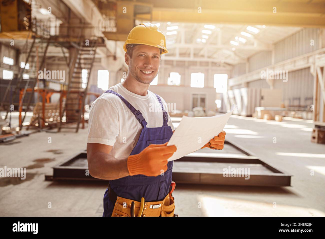Cheerful male worker holding building architectural plan Stock Photo