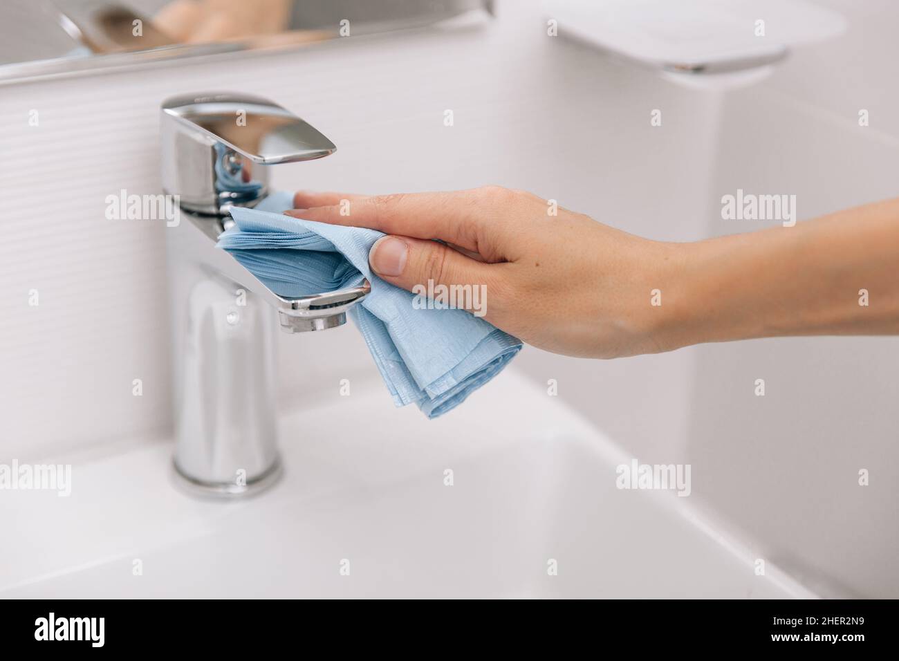 Cleaning the sink faucet with a microfiber cloth. Cleaning the bathroom