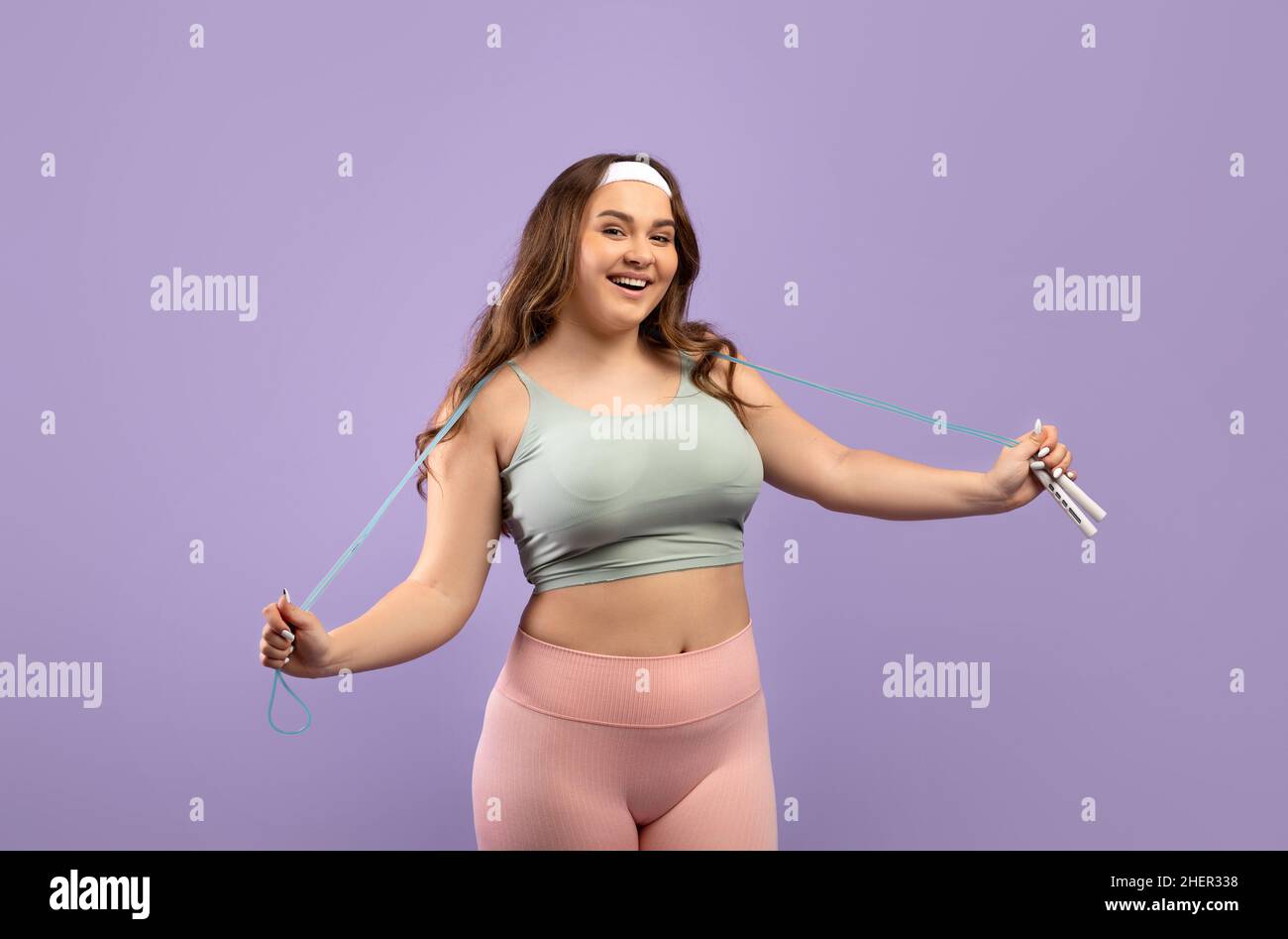 Satisfied funny millennial european woman plus size in sports uniform with skipping rope ready to training Stock Photo