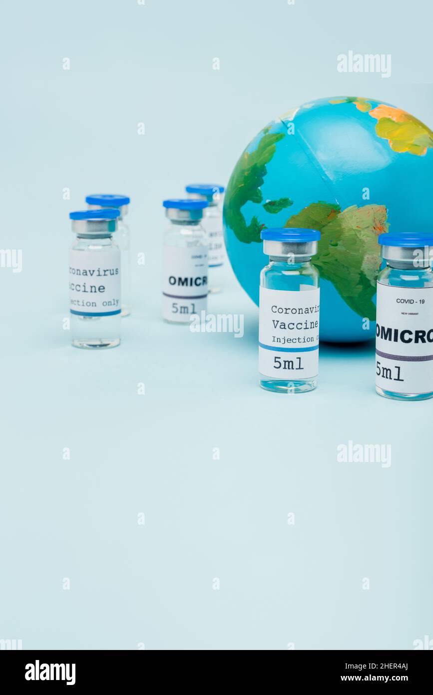 covid-19 and omicron strain vaccine jars near globe on blue,stock image Stock Photo