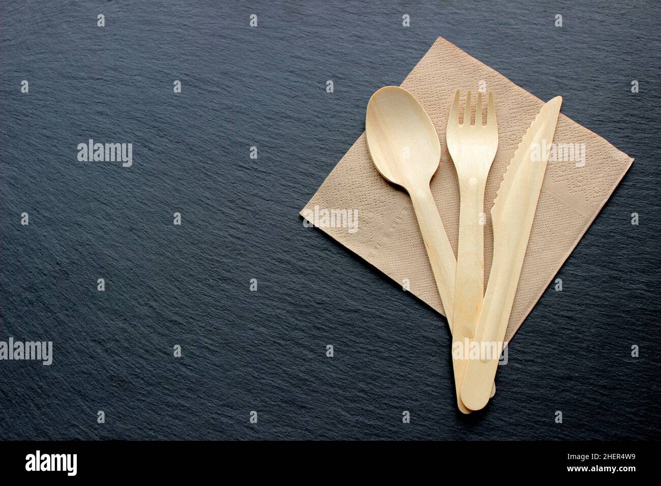 Eco craft paper tableware. Paper cups, dishes and wooden cutlery on dark background. Recycling concept. Top view Stock Photo
