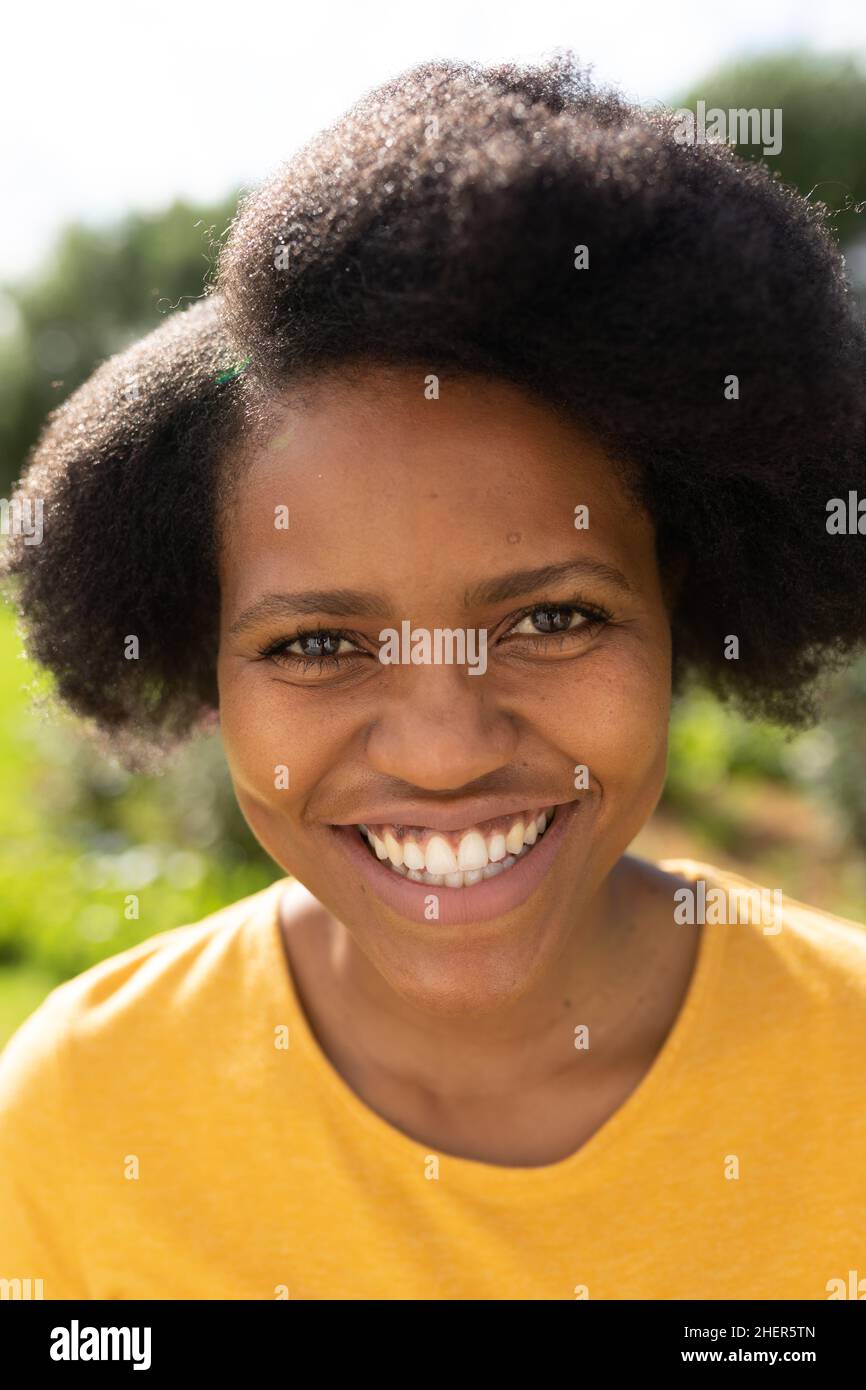 Closeup portrait of cheerful mid adult woman with afro hairstyle in backyard on sunny day Stock Photo