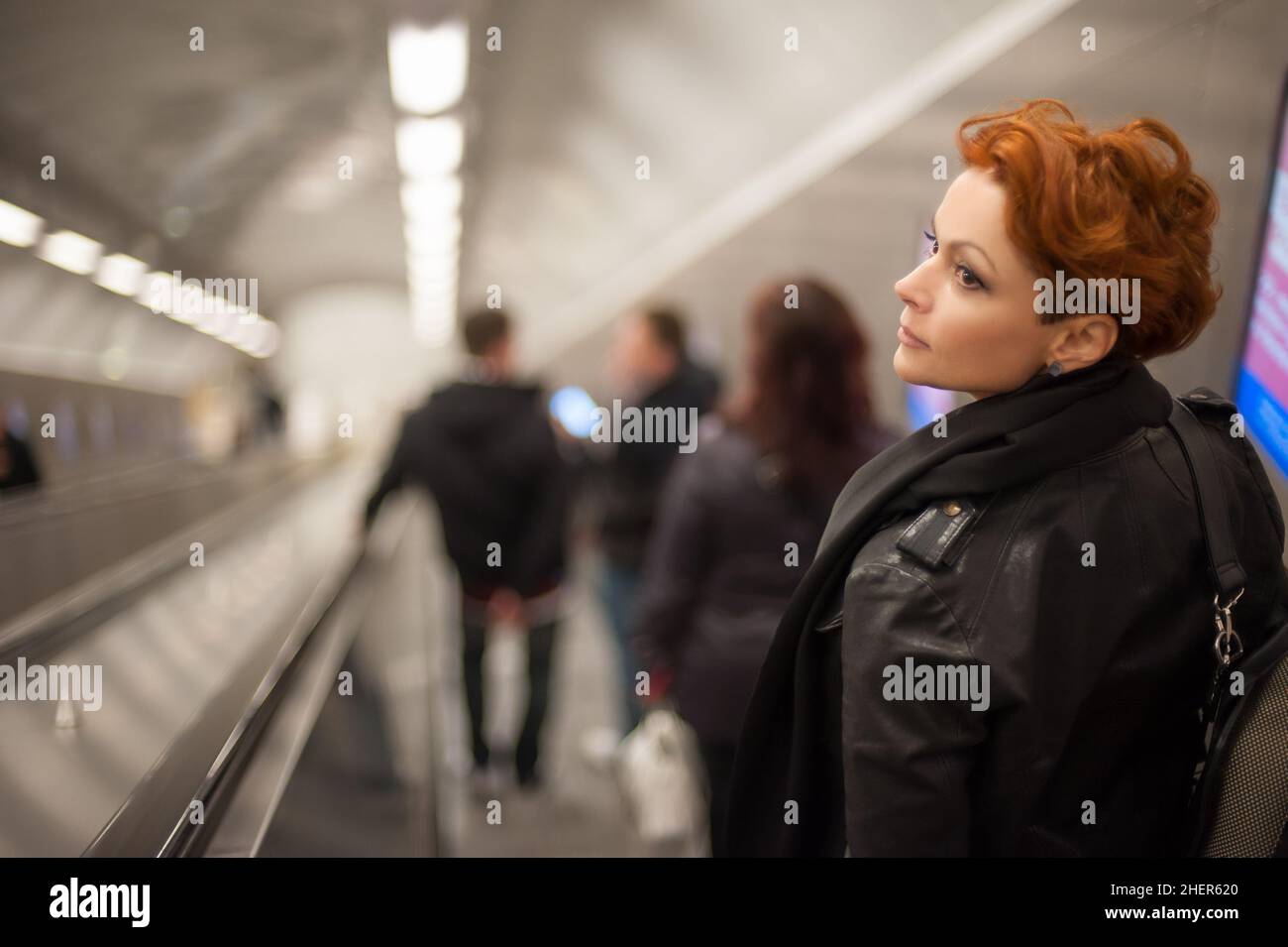 Woman coming down to the metro station through the escalator tounel Stock Photo