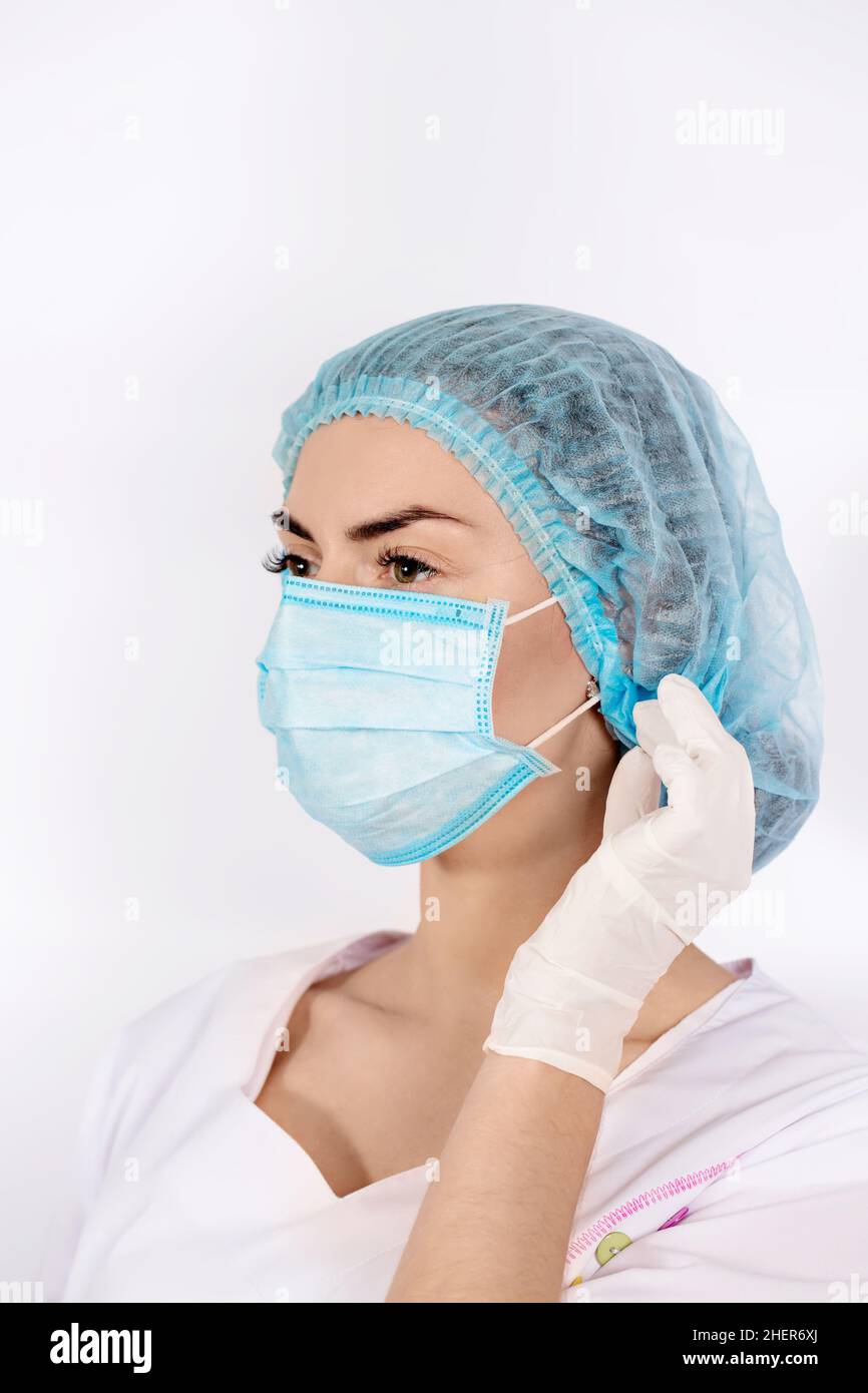 Nurse wearing a medical cap puts on a protective mask. Coronovirus ...