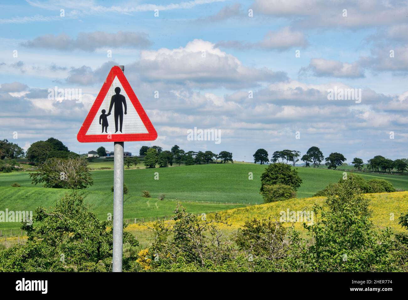 Rural scene with red triange warning sign pedestrians in road. Stock Photo