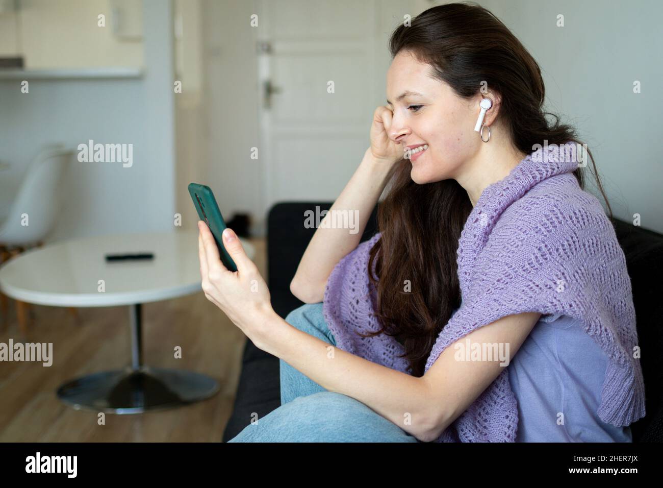A happy woman in headphones is talking to someone using smartphone ...