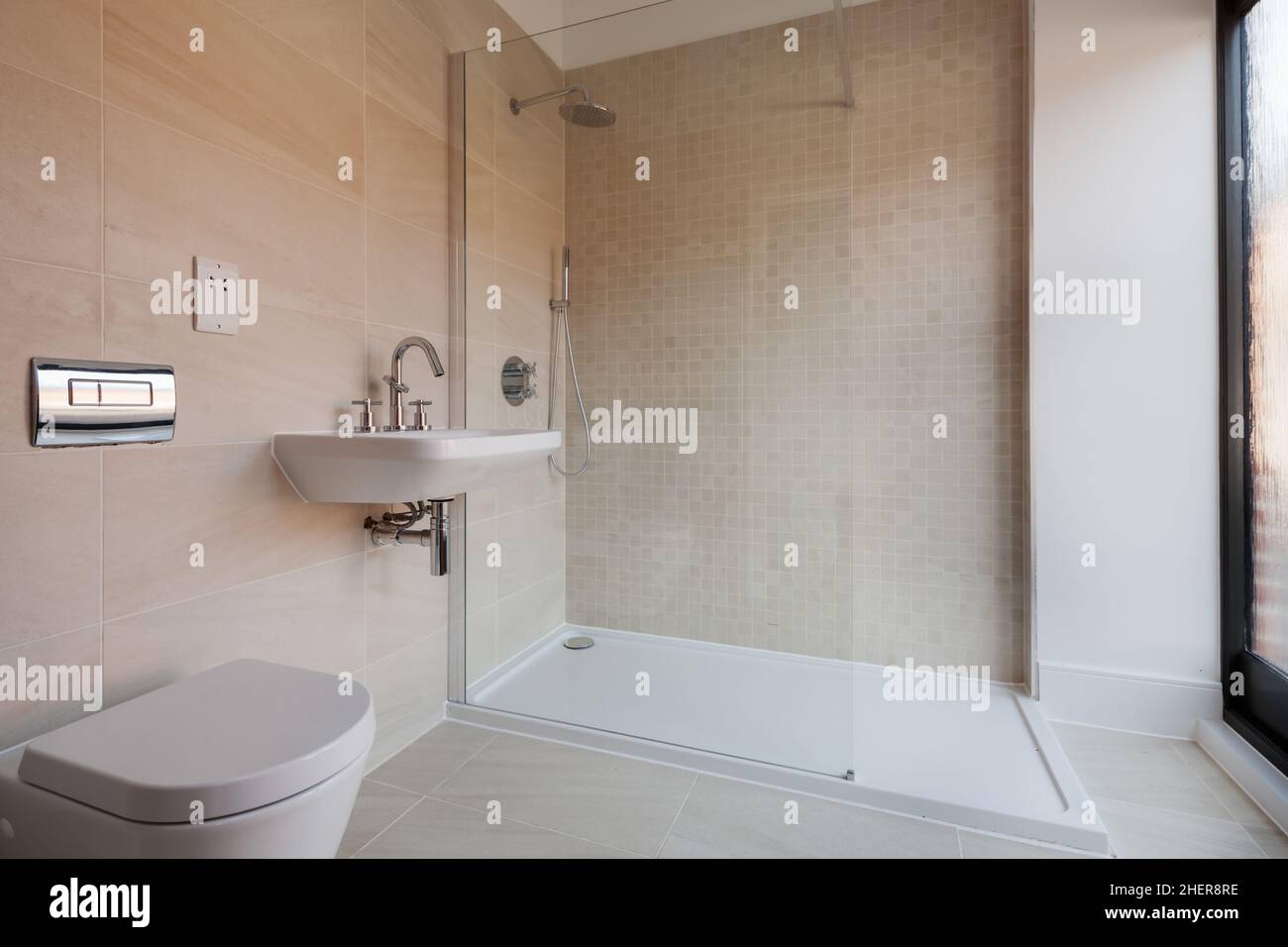 Cowlinge, Suffolk, England - 28 March 2019: Luxury generic bathroom suite with tiled walls and floor glass fronted shower cubicle , sink, toilet and w Stock Photo