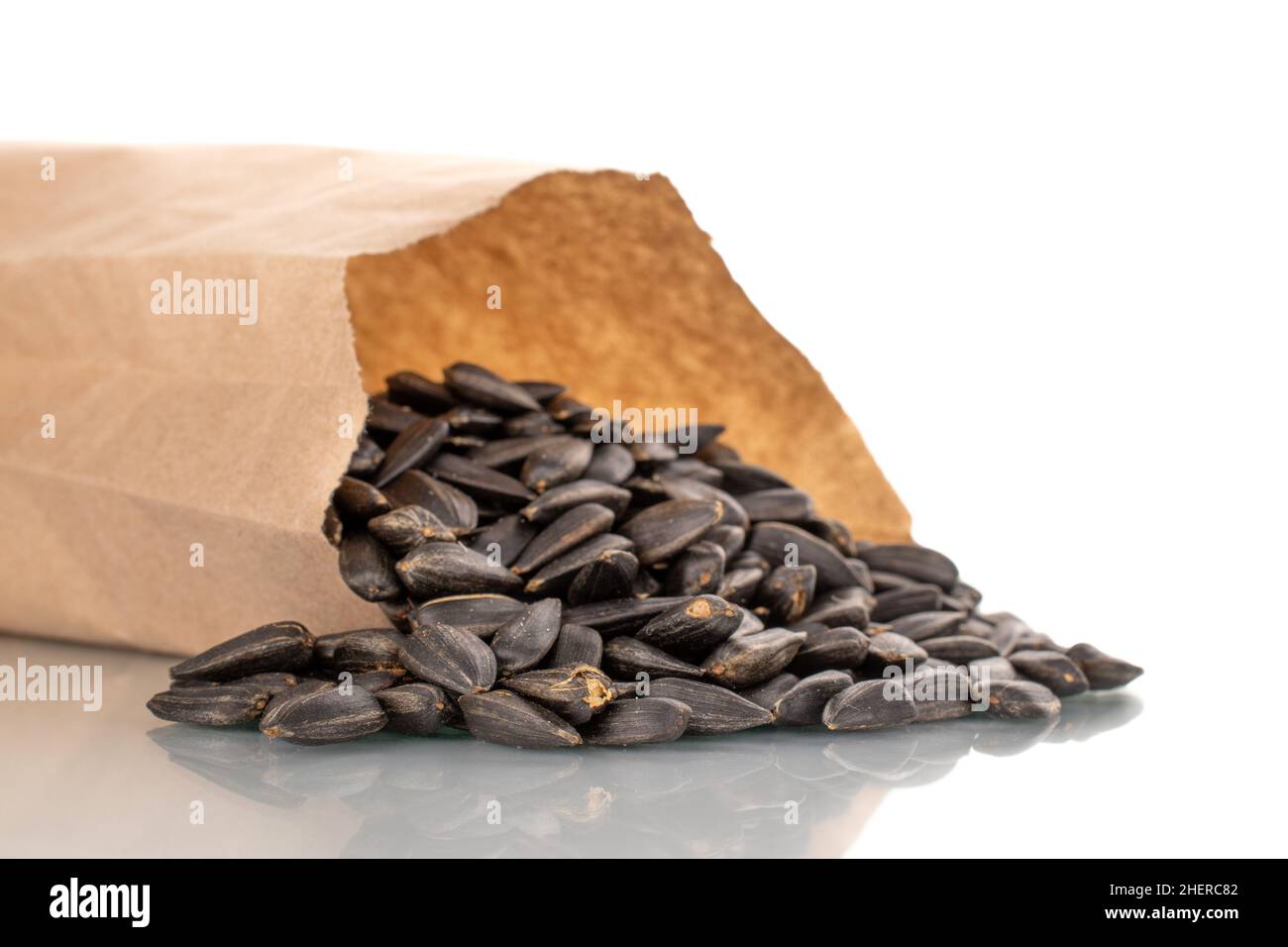 Many fragrant sunflower seeds in a paper bag, closeup, isolated on