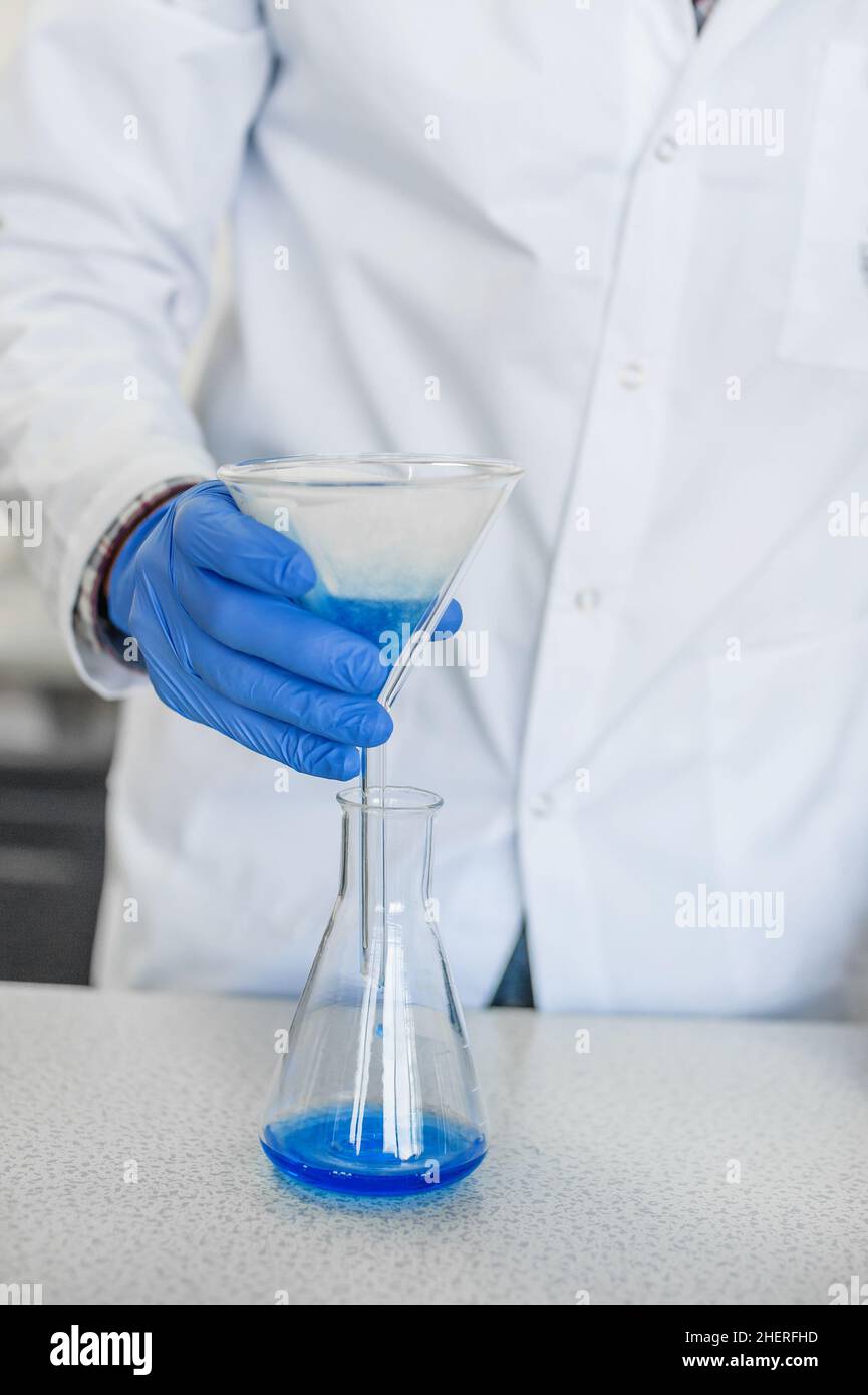 Scientific laboratory technician performs tests and pouring blue liquid
