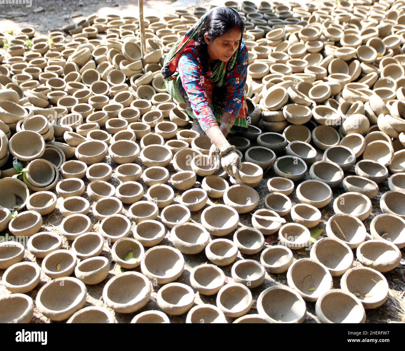 DECEMBER15,2021,DHAKA,BANGLADESHA potter arranges clay utensils at a verandah to dry them in