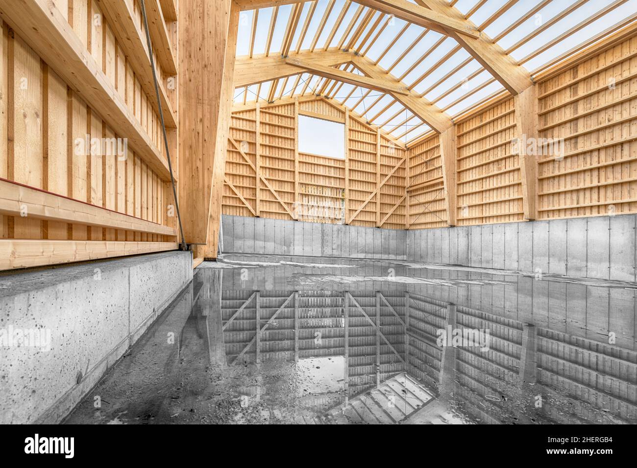 Large engineering hall in timber construction with a concrete base wall and reflection of the construction in the water Stock Photo