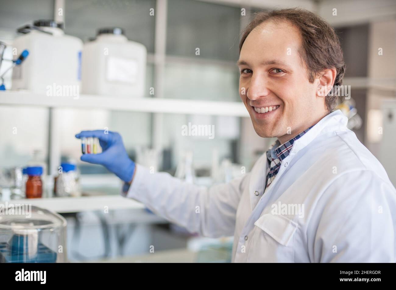 Male lab technician holding a test tube with sample in the medical or