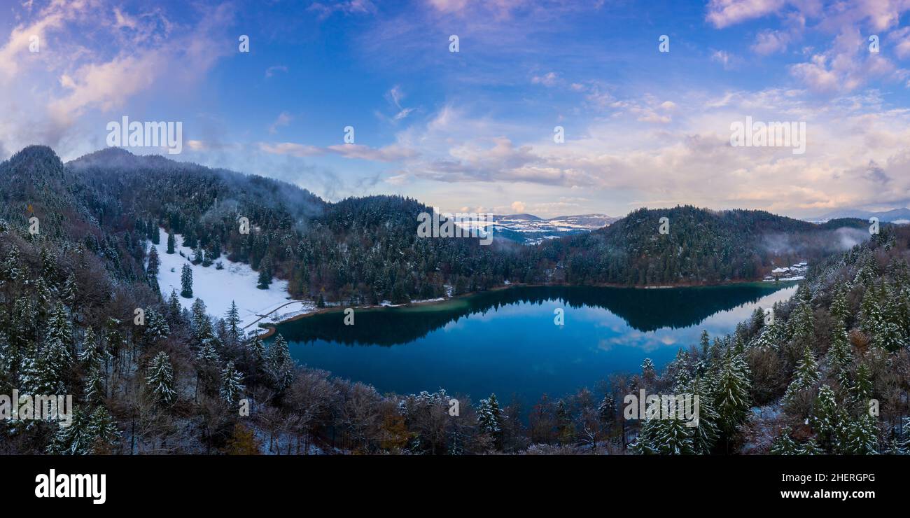 lake Alatsee between snowy mountains with forest and nice cloudy sky Stock Photo