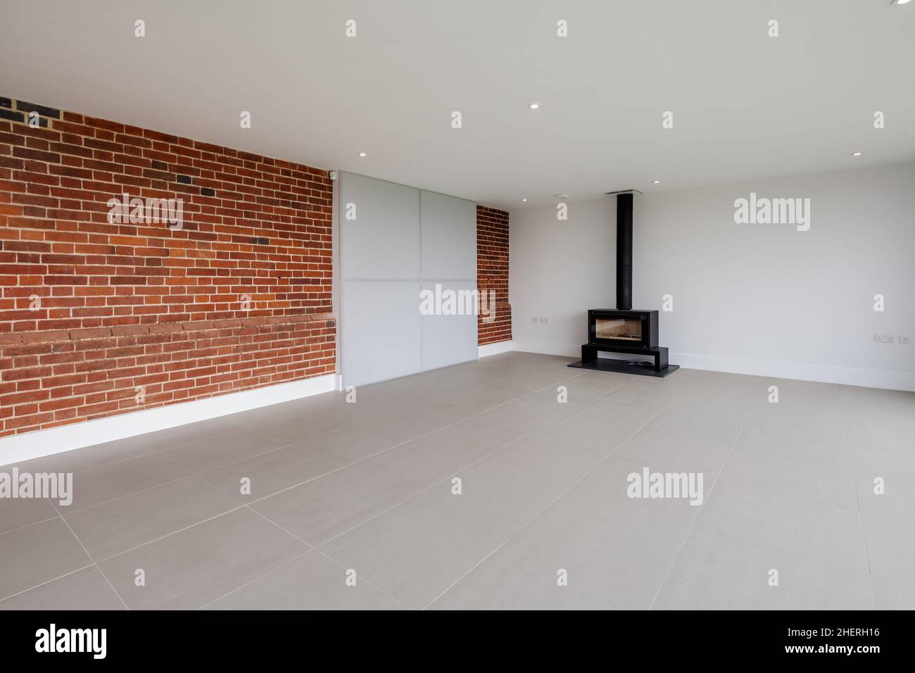 Cowlinge, Suffolk, England - 19 April 2019: Brand new vacant lounge in recently constructed suffolk home with original exposed brickwork to one wall a Stock Photo