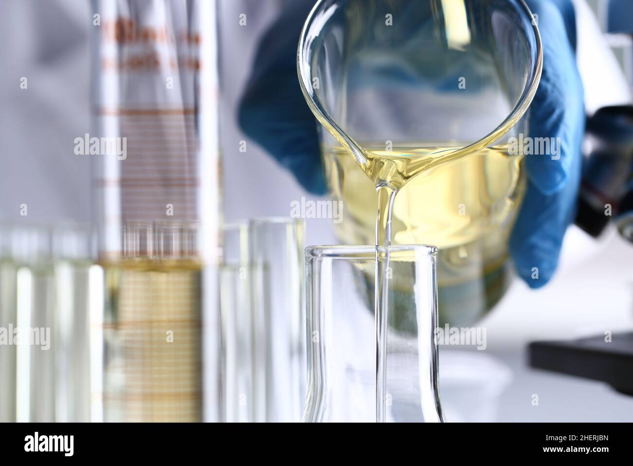 Hand pours yellow liquid into test tube closeup Stock Photo