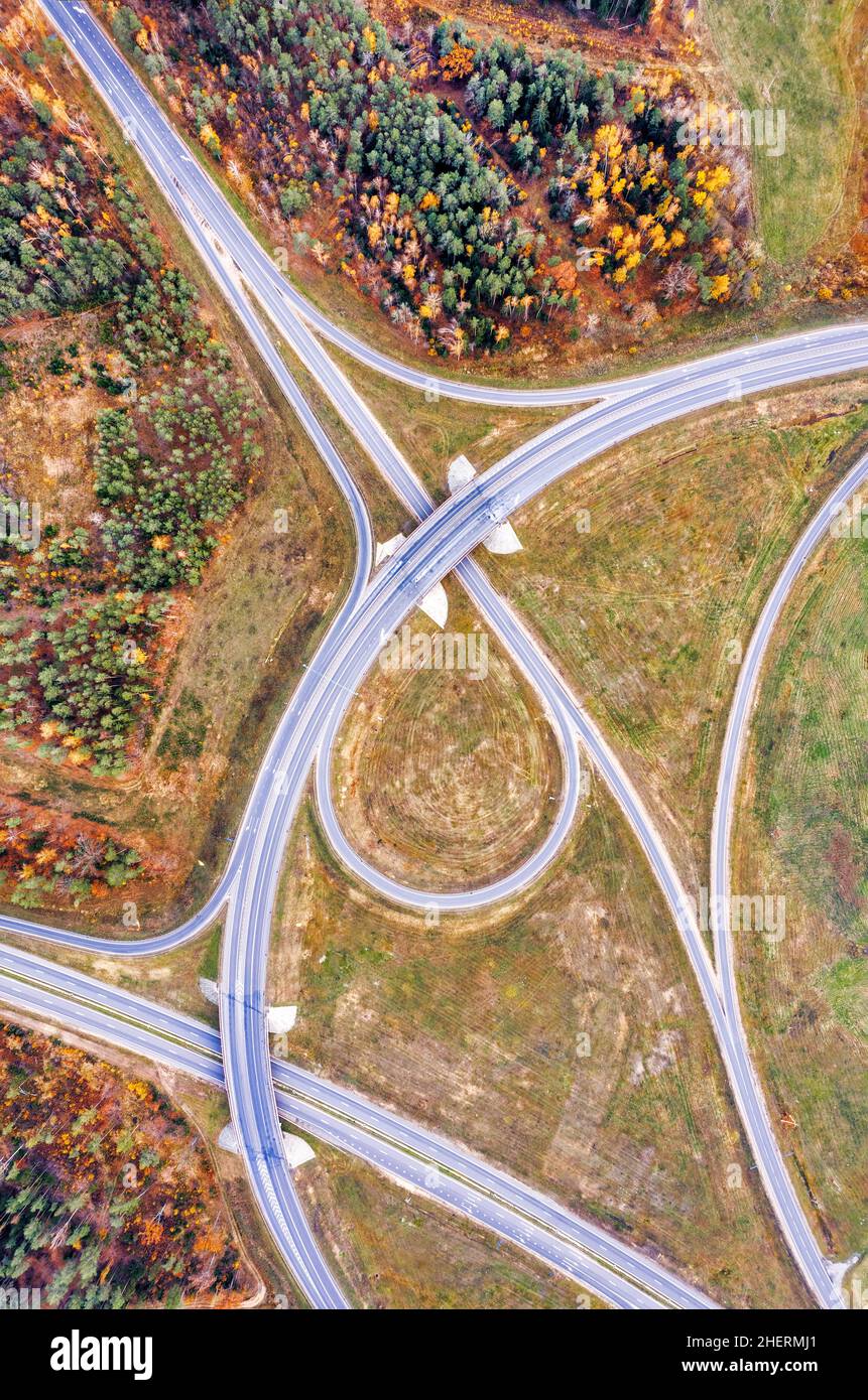 Aerial view on circular road intersection in beautiful autumn forest. Beautiful landscape with empty rural road, trees with red and orange leaves. Hig Stock Photo