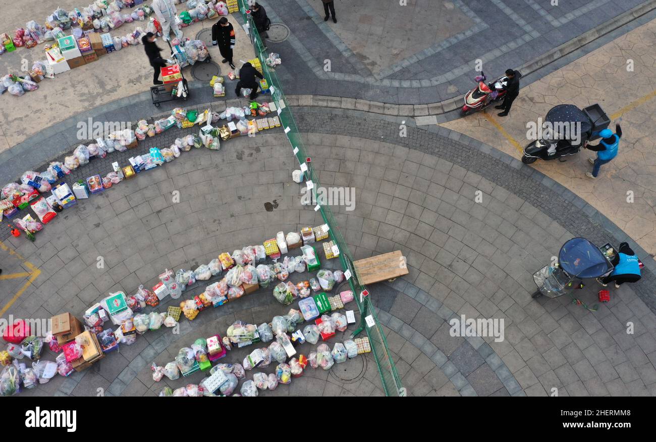 Xi'an. 12th Jan, 2022. Aerial photo take on Jan. 12, 2022 shows government workers and volunteers receiving daily necessities ordered by residents under home quarantine in Yanta District of Xi'an, capital of northwest China's Shaanxi Province. In Yuchang Sun City Community of Xi'an, 20 government workers who were sent to join the frontline staff working in the residential quarter and nearly a hundred volunteers are working against the clock to deliver daily necessities to residents under home quarantine. Credit: Tao Ming/Xinhua/Alamy Live News Stock Photo
