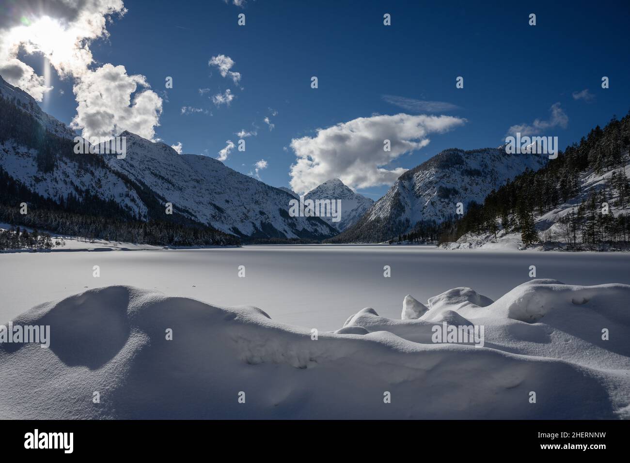 Snowy lake Plansee in Breitenwang at winter blue sky and clouds Stock Photo