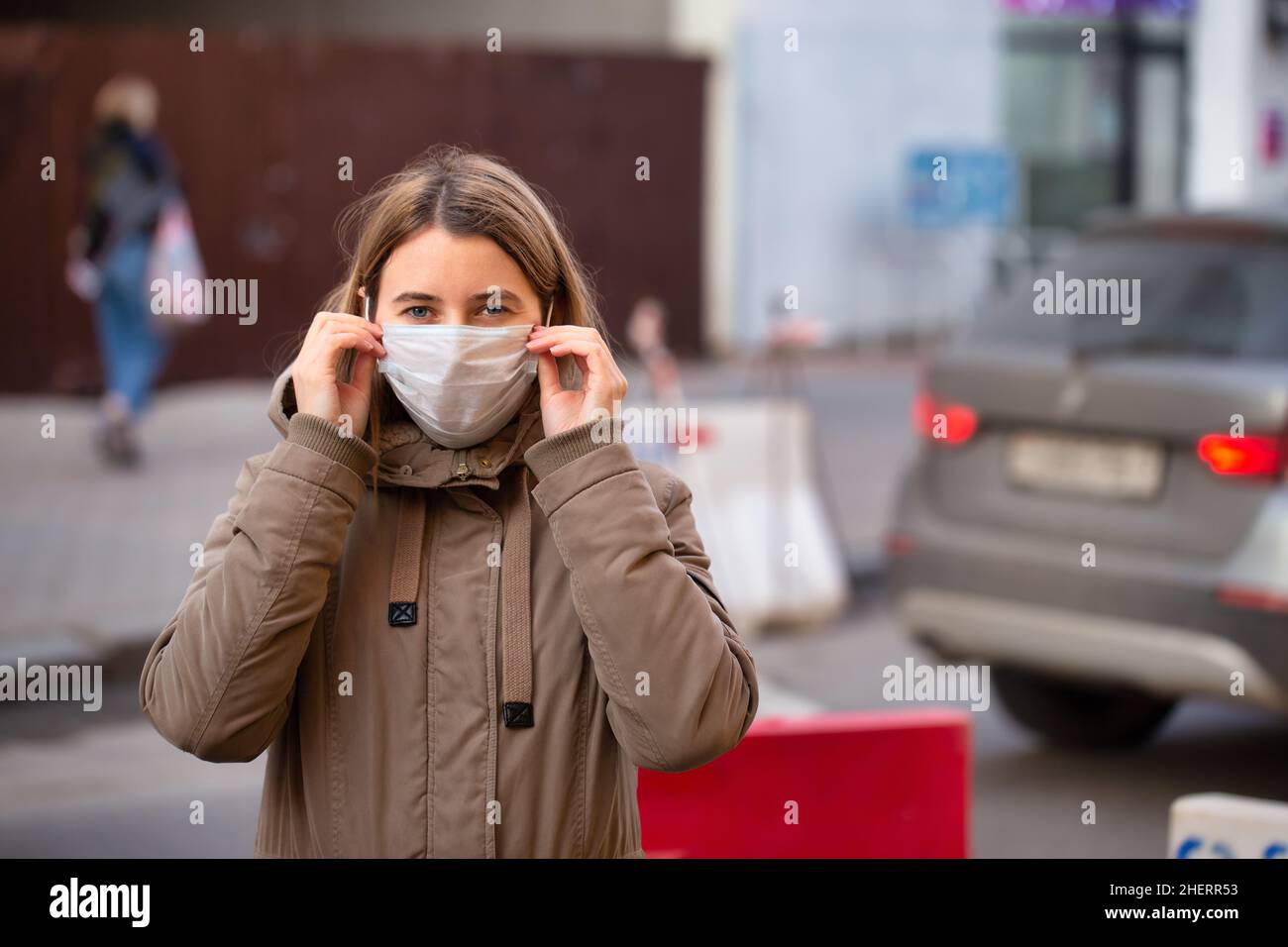 Woman puting on surgical face mask on street of Milano. Coronavirus outbreak in Europe. Flu epidemic spread prevention Stock Photo