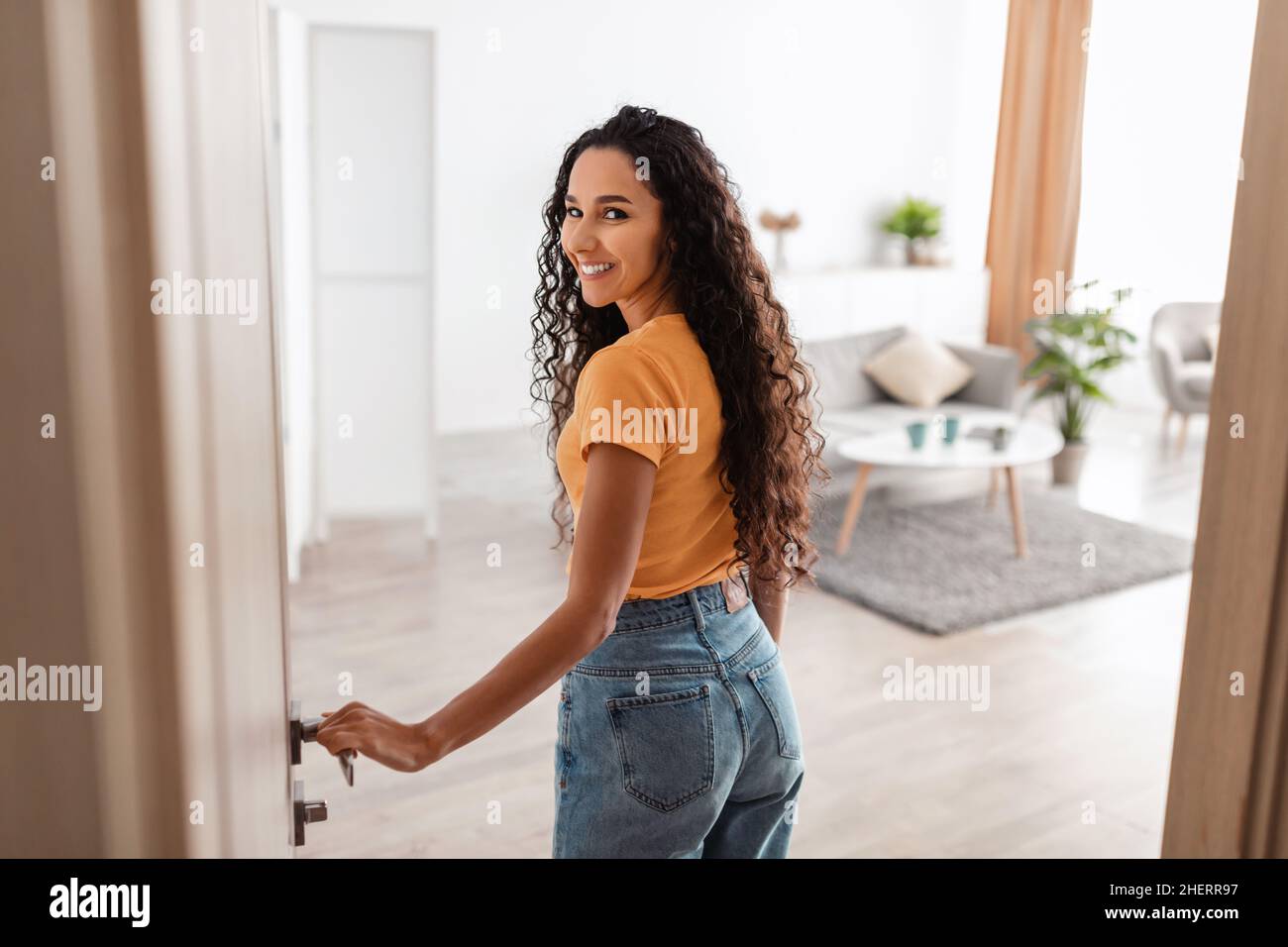 Back view of excited young woman walking in apartment Stock Photo