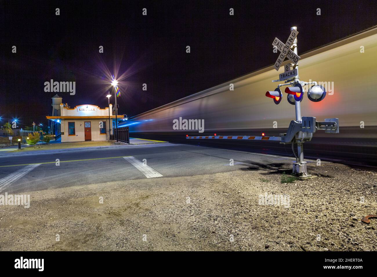 Railroad crossing with passing train by night at route 66 Stock Photo