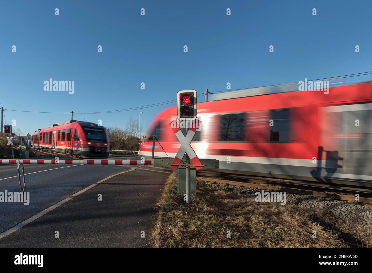 On a single-track railway line, two oncoming trains at a level crossing with barriers, one train, Bavaria, Germany Stock Photo