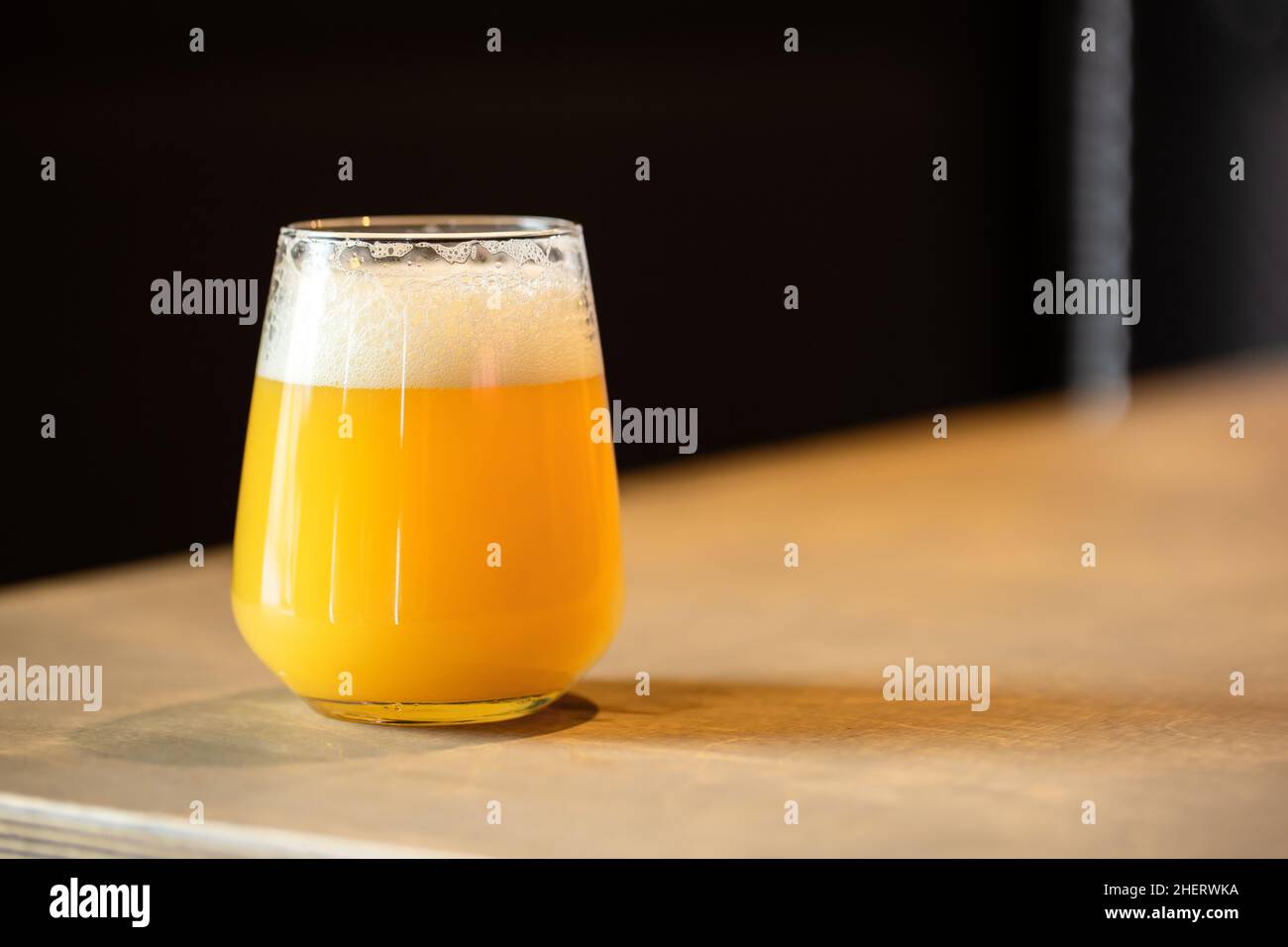 Hazy NEIPA New England IPA pale ale beer, on wood surface, rich frothy foam head with copy space Stock Photo