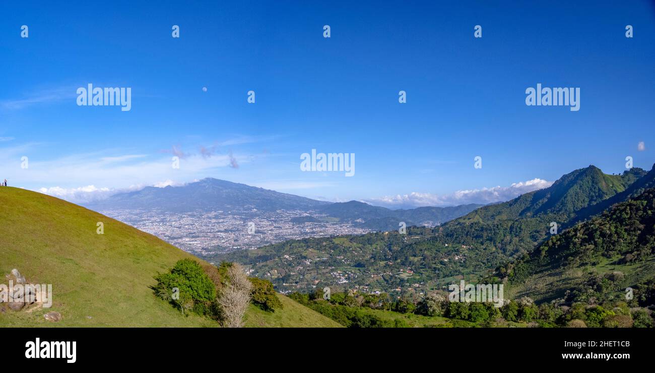 Overlooking the entire city of San Jose Costa Rica and the mountains and volcanoes in the background under blue sky Stock Photo