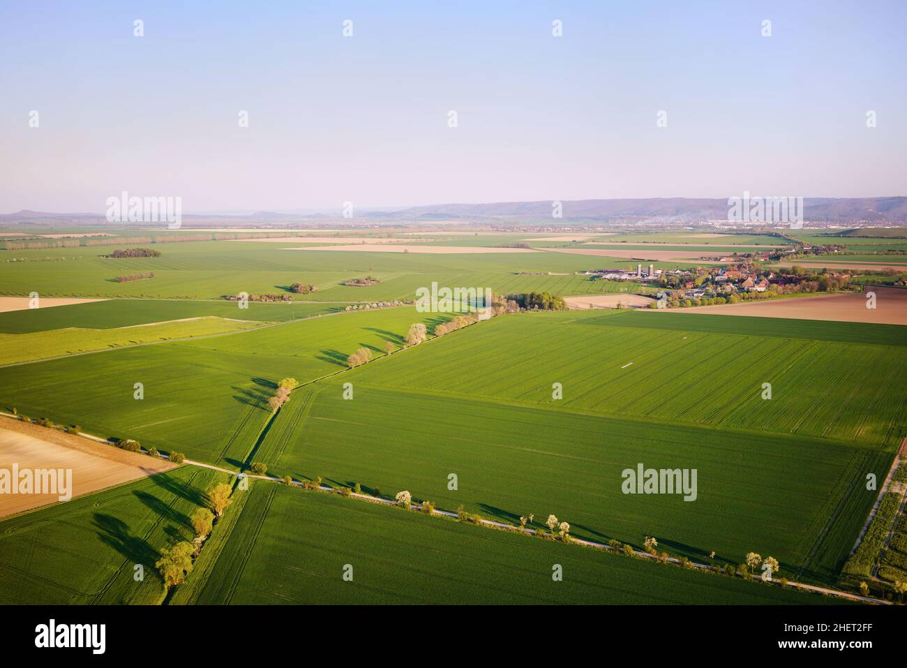 Aerial view of fresh green fields, village and farmland. Rural countryside and agriculture