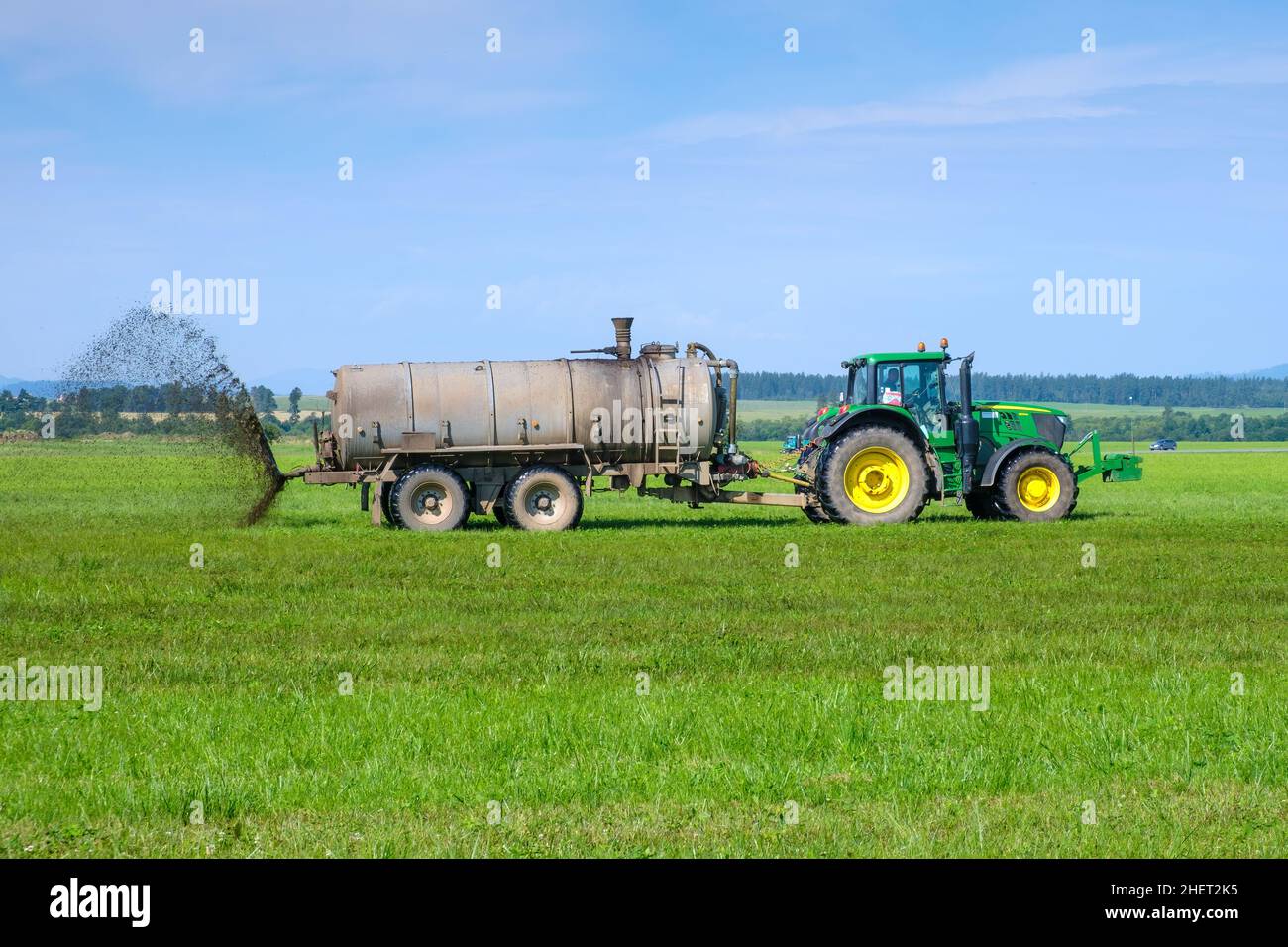 A big tractor spreading fertilizer to improve the harvest on pasture meadow. Landfarming concept. January 2022, Poprad, Slovakia.  Stock Photo