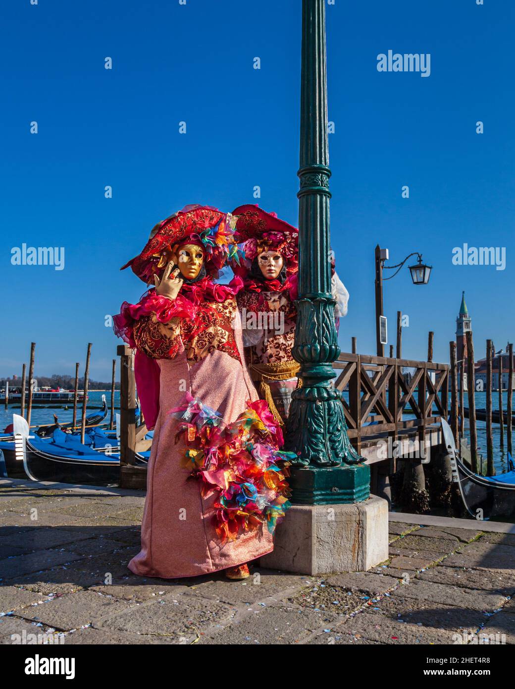 Man and woman in colourful historic Venetian fancy dress costumes, pose by the lagoon at Venice Carnival, Carnevale di Venezia, Italy Stock Photo
