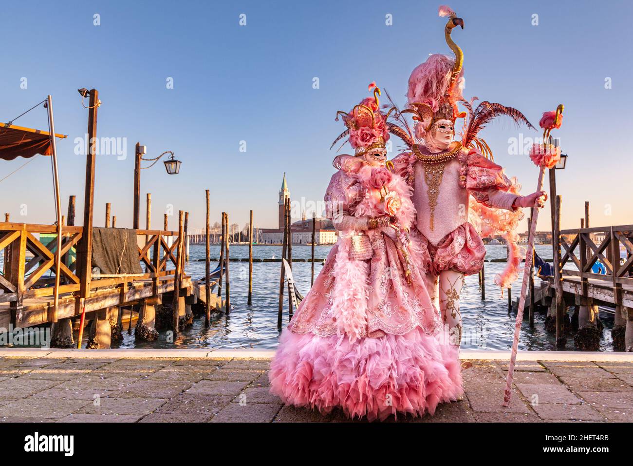 Man and woman in pink flamingo historic  fancy dress rococo costumes, pose by the lagoon at Venice Carnival, Carnevale di Venezia, Italy Stock Photo