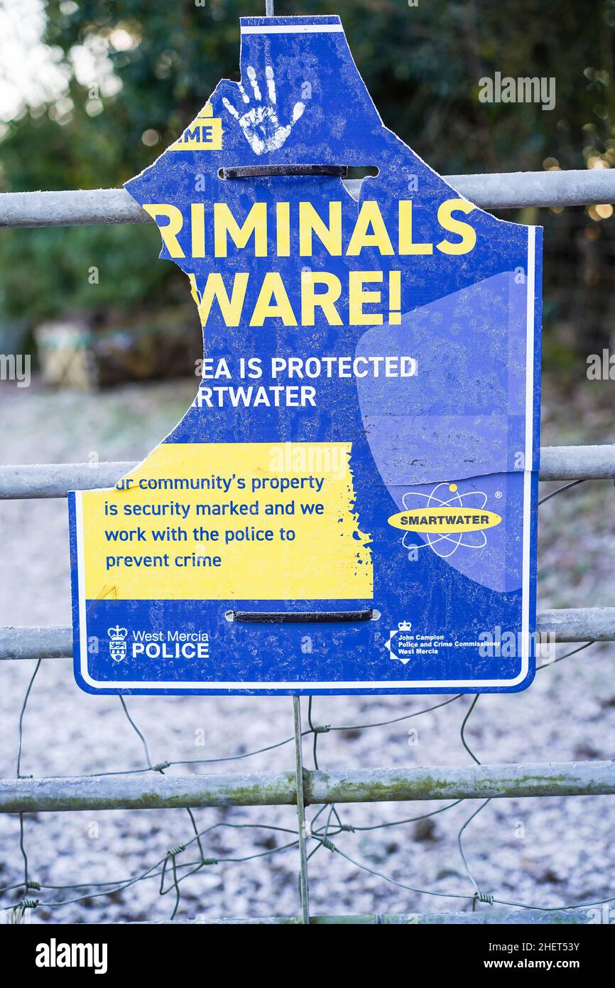 Close up of isolated, crime prevention sign with public advice: 'Criminals Beware' - broken/ damaged & vandalised by local criminals. Irony. Stock Photo