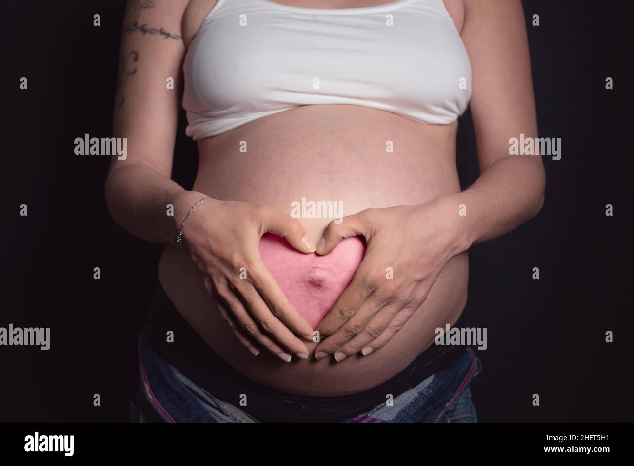 it's a girl pink heart with hands on belly of pregnant mother Stock Photo