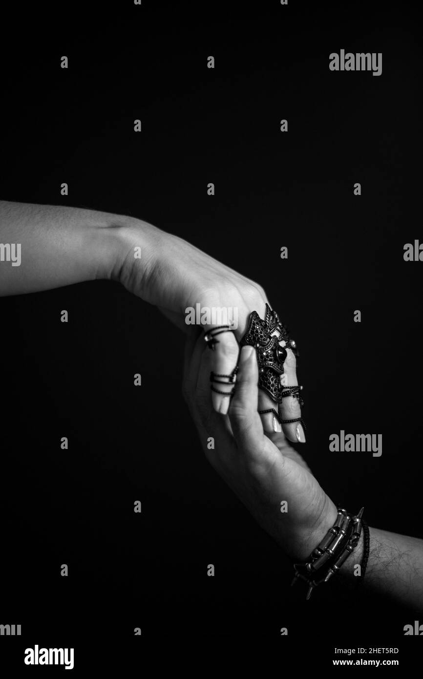 Close up of female and male hands holding, wearing jewelry. Soft focus. Black and white Stock Photo