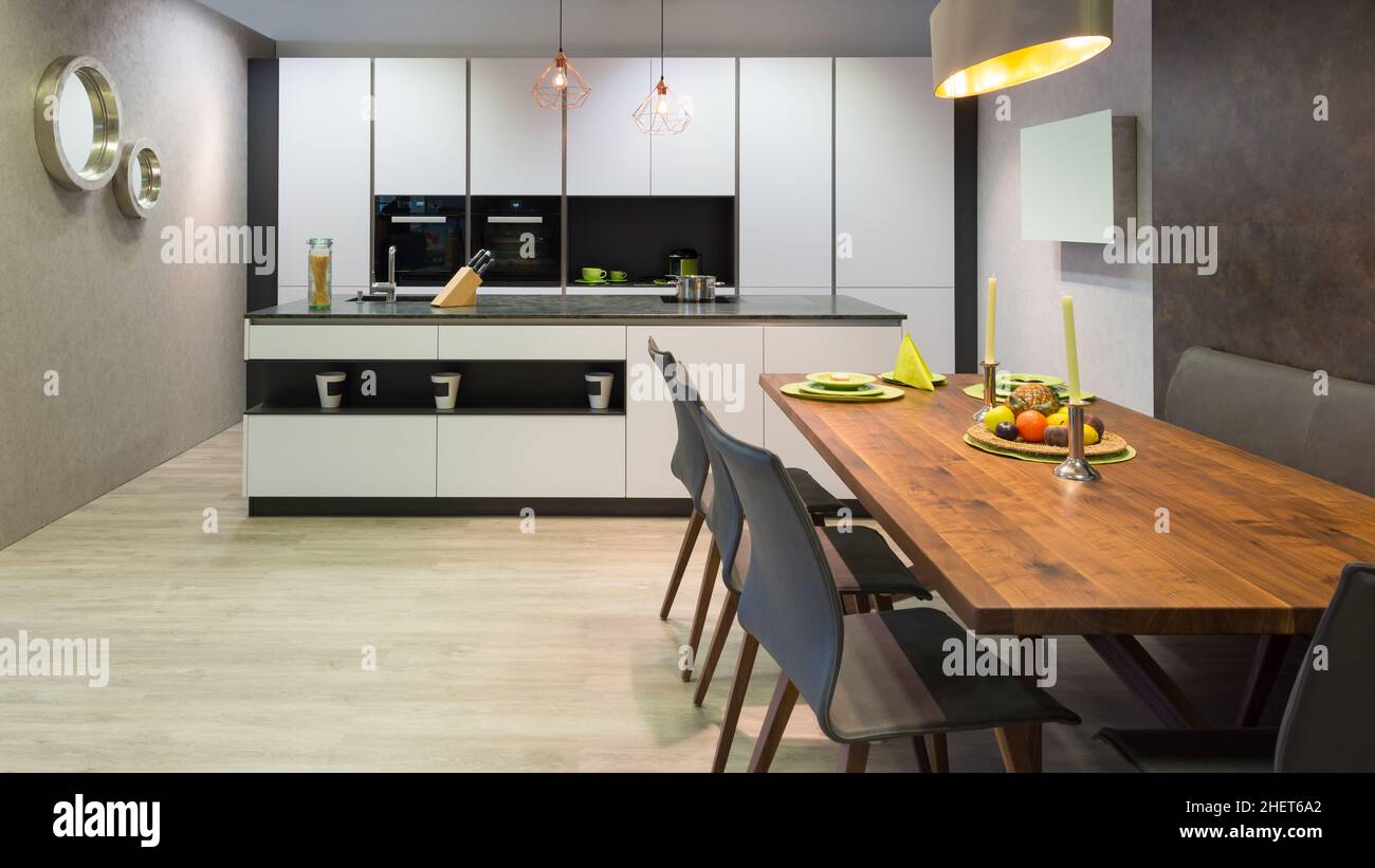 flat white kitchen with island unit and wooden dinner table Stock Photo