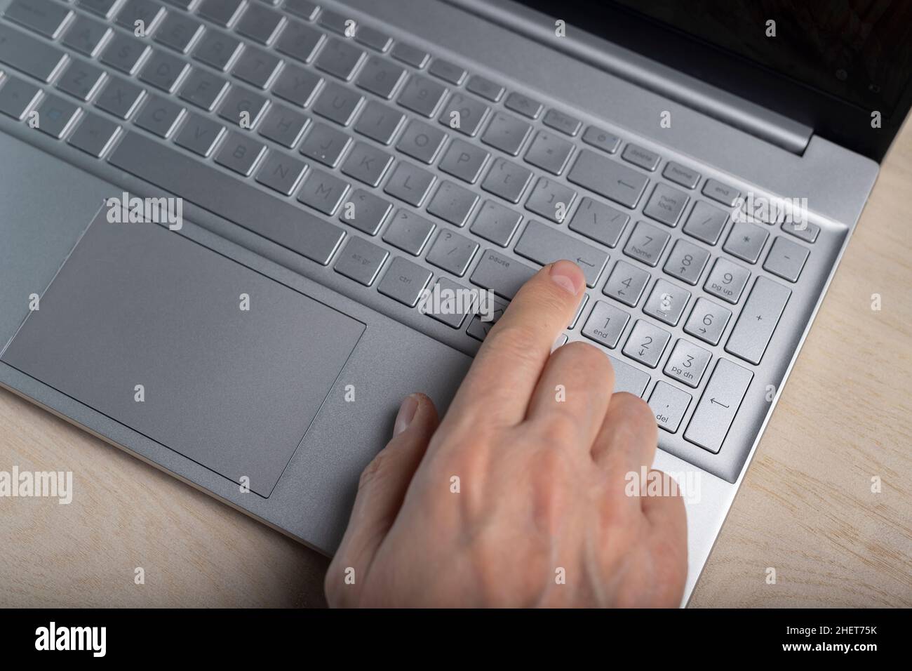 Hand on laptop keyboard, tapping and pressing button with finger closeup. Stock Photo