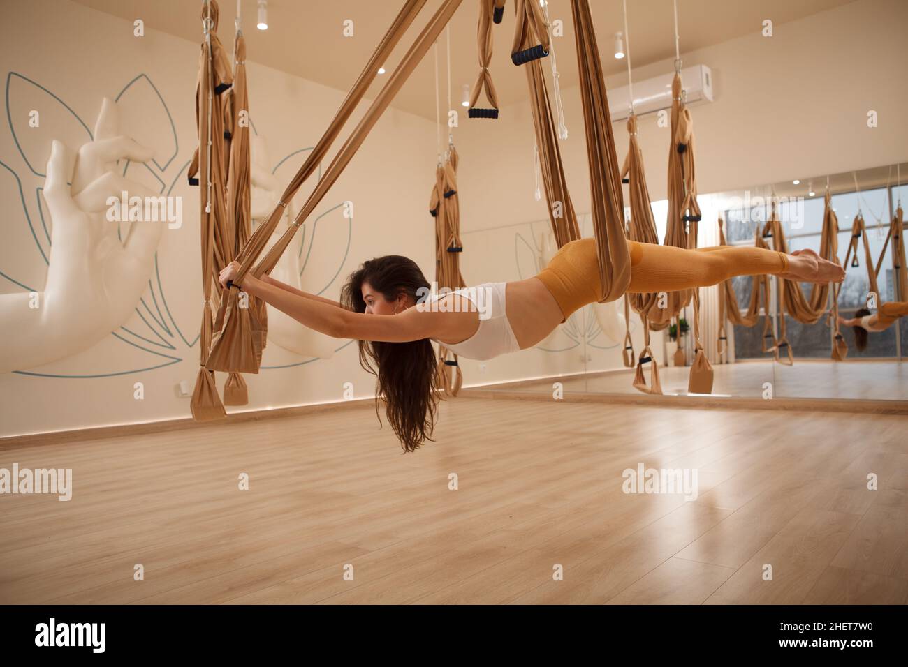 Full length shot of a long haired fit young woman enjoying practicing aerial yoga at sport studio Stock Photo