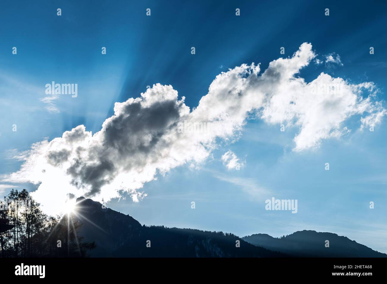 light rays through clouds over mountain top at blue sky Stock Photo