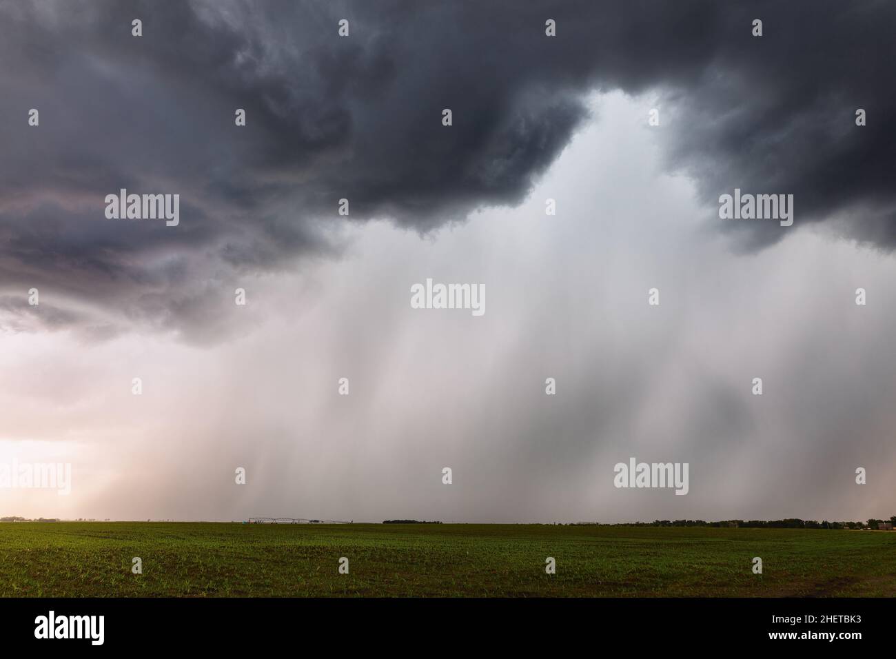 Heavy rain falling from dark clouds beneath a strong storm near Tappen