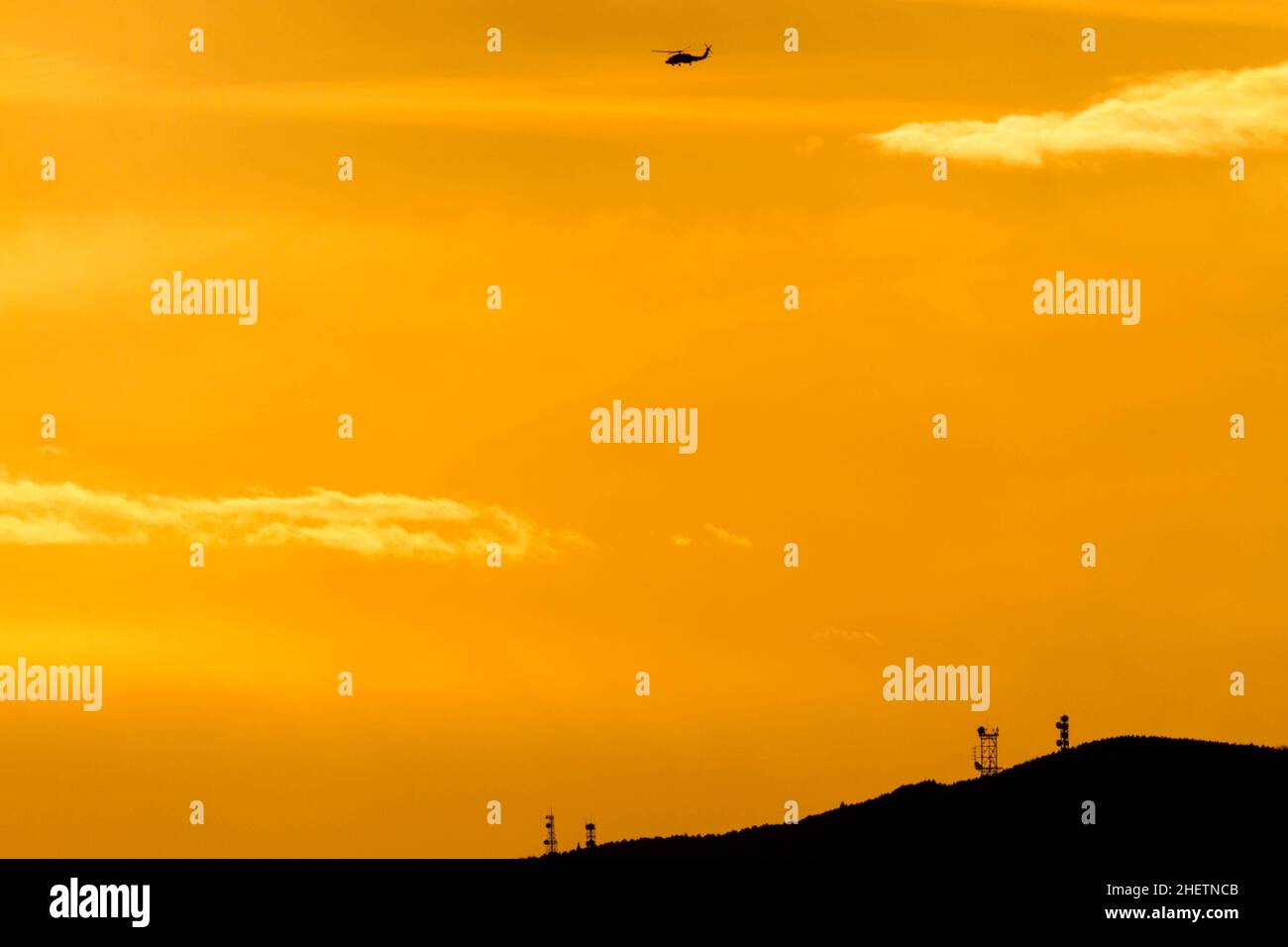 A Sikorsky SH-60 Seahawk helicopter in silhouette at sunset, flying near Naval Air Facility, Atsugi airbase in Kanagawa, Japan. Stock Photo