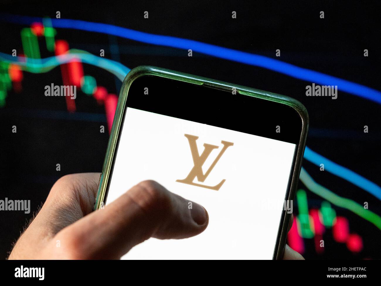 China. 09th Dec, 2021. In this photo illustration the French luxury fashion brand Louis Vuitton (LV) logo seen displayed on a smartphone with an economic stock exchange index graph in the background. (Photo by Budrul Chukrut/SOPA Images/Sipa USA) Credit: Sipa USA/Alamy Live News Stock Photo