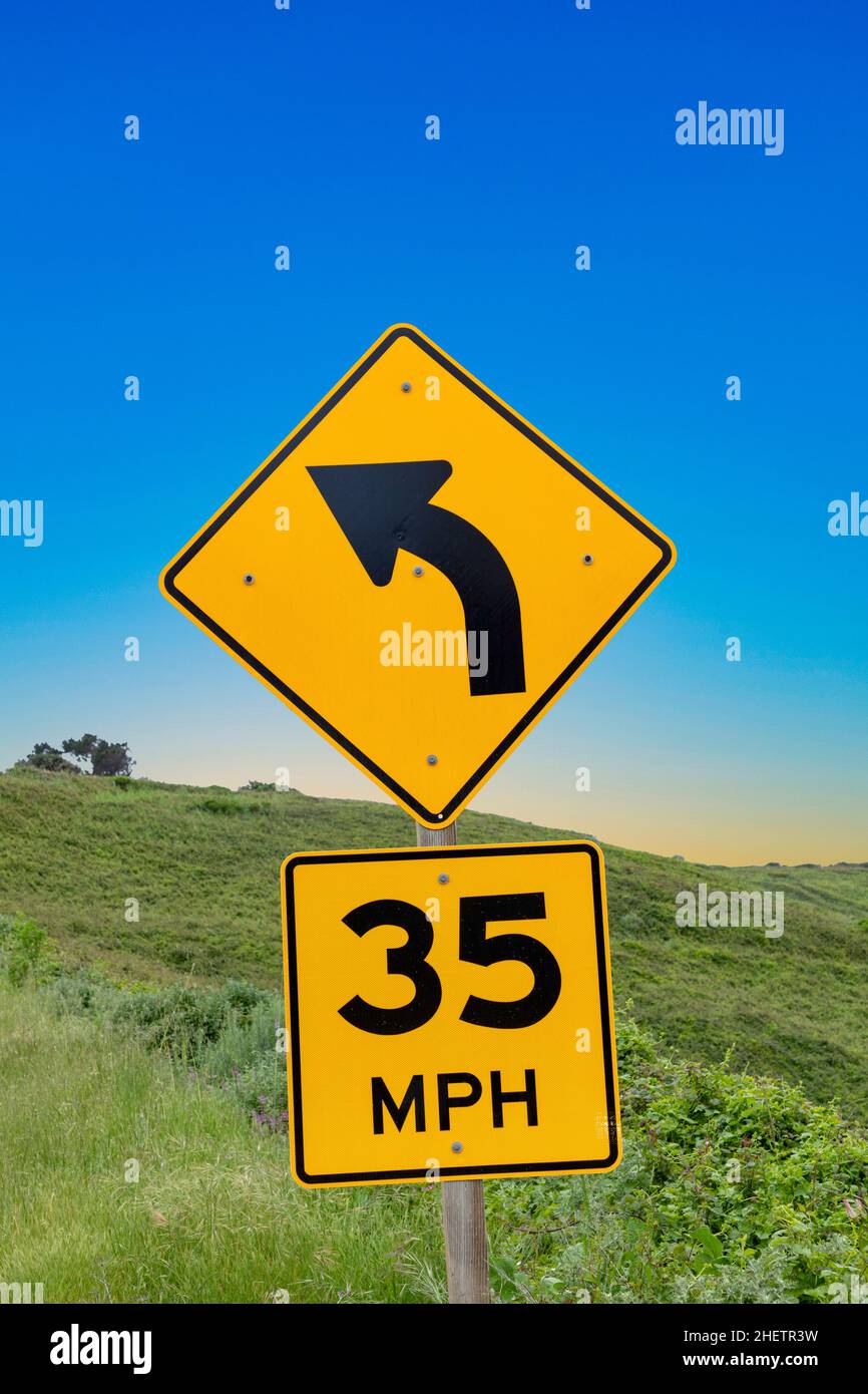 yellow street sigh 35 MPH at Cabrillo highway with sign winding road under blue sky Stock Photo
