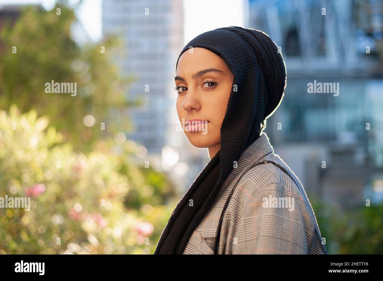 Portrait of a muslim adult woman wearing a black headscarf looking at camera in the park Stock Photo