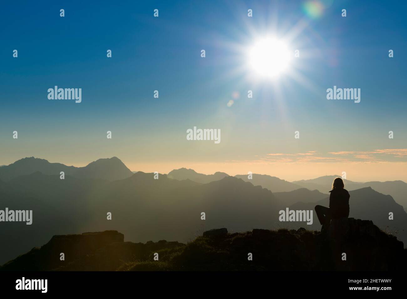 lonely thinking person on peak of mountain at sunset Stock Photo